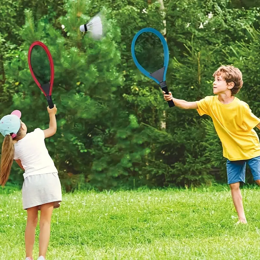 Two children playing with colorful badminton rackets on a grassy field.