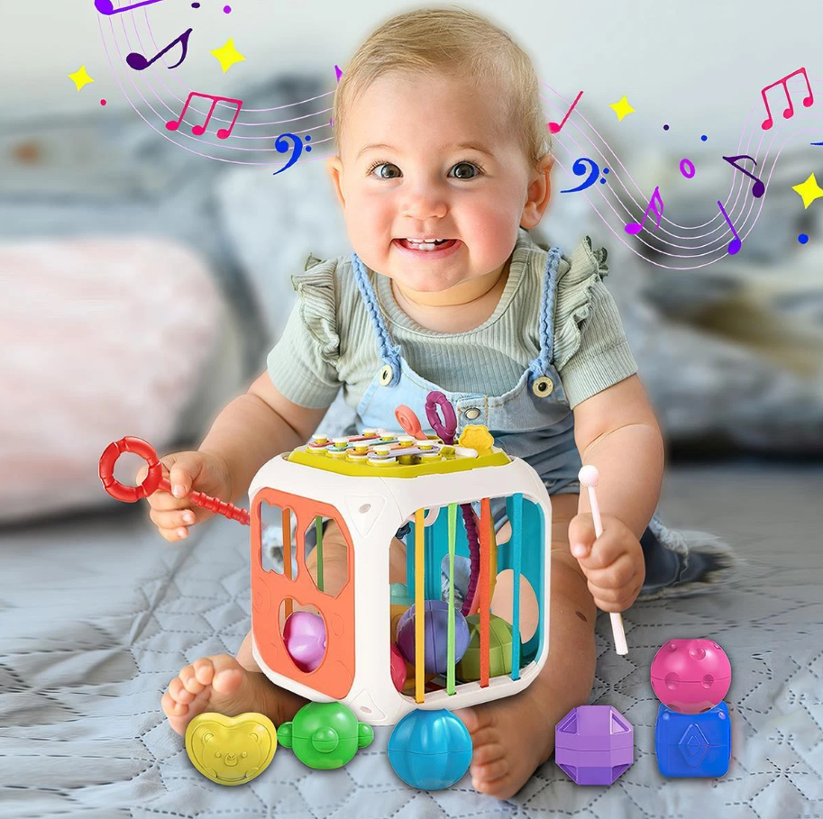Baby playing with a colorful toy cube on a bed with musical notes around