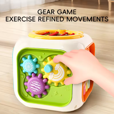 Colorful gear toy cube with a hand interacting with it on a wooden floor.