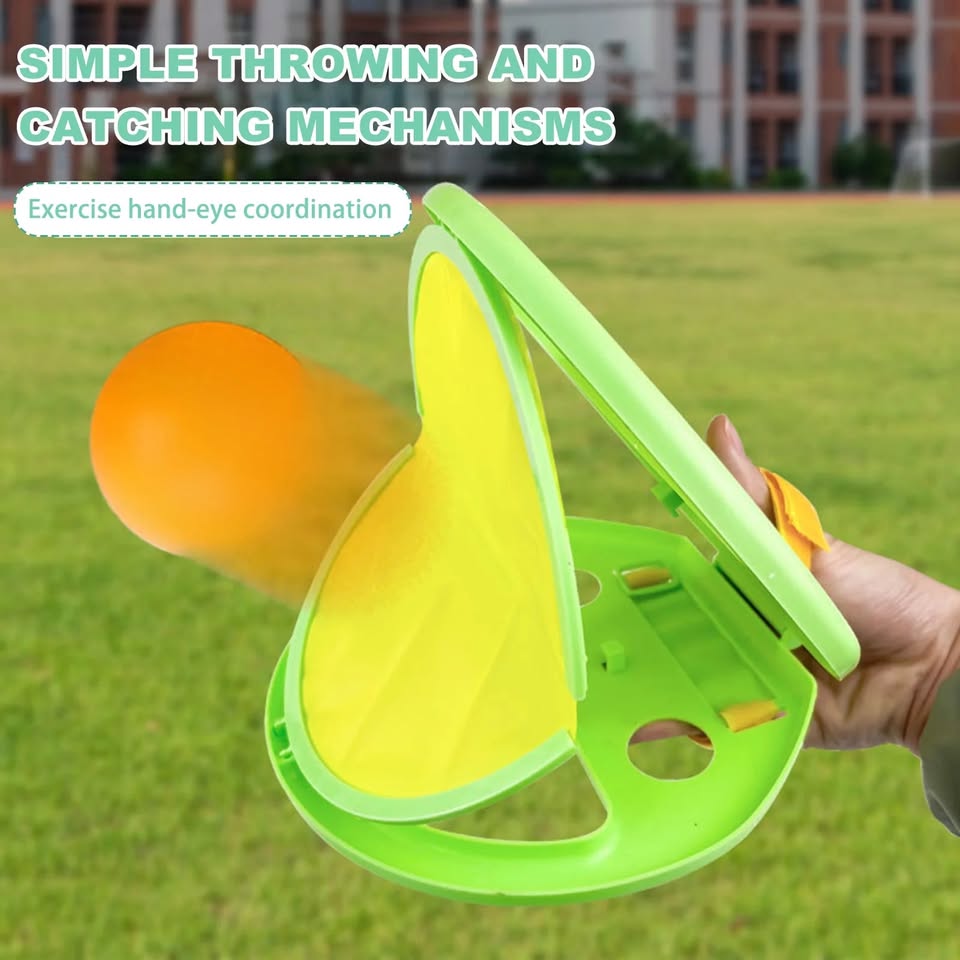 Green throwing and catching mechanism with an orange ball on a grassy field.