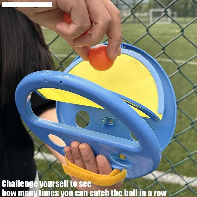 Person holding a blue and yellow ball launcher with a red ball on a sports field background.