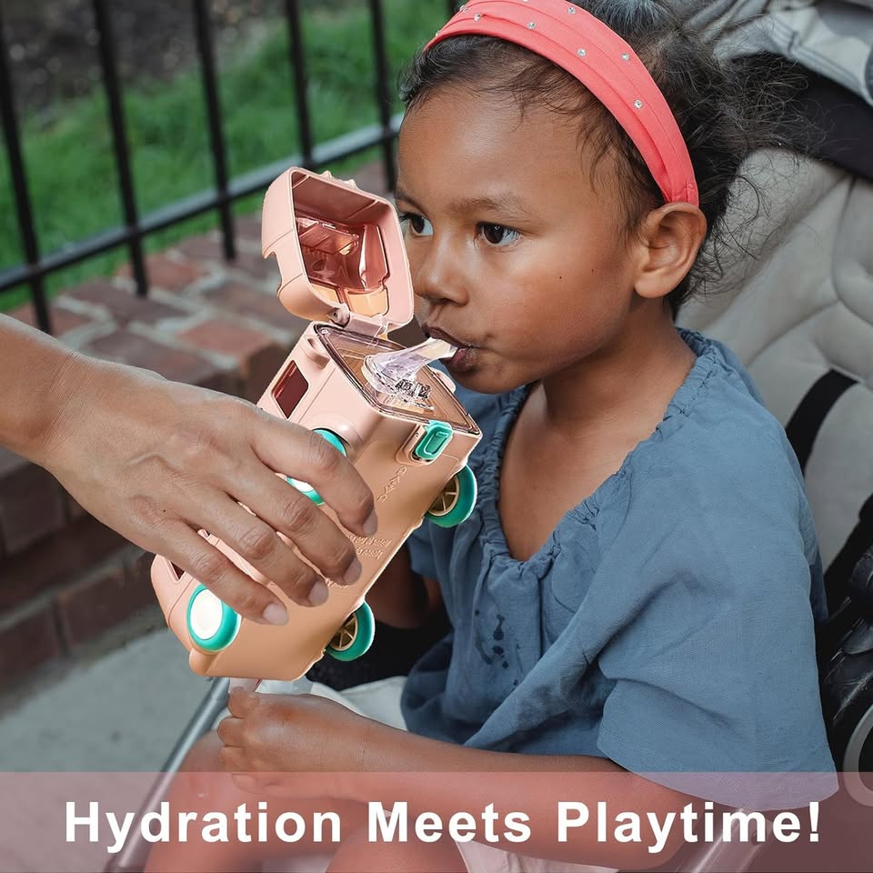 Child drinking from a rose gold water bottle with green accents, sitting outdoors.