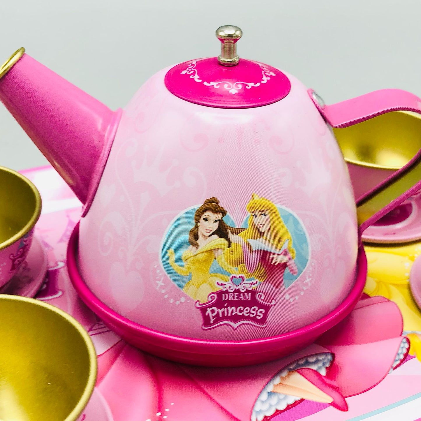 Pink toy tea set with Disney Princess design on a gray background