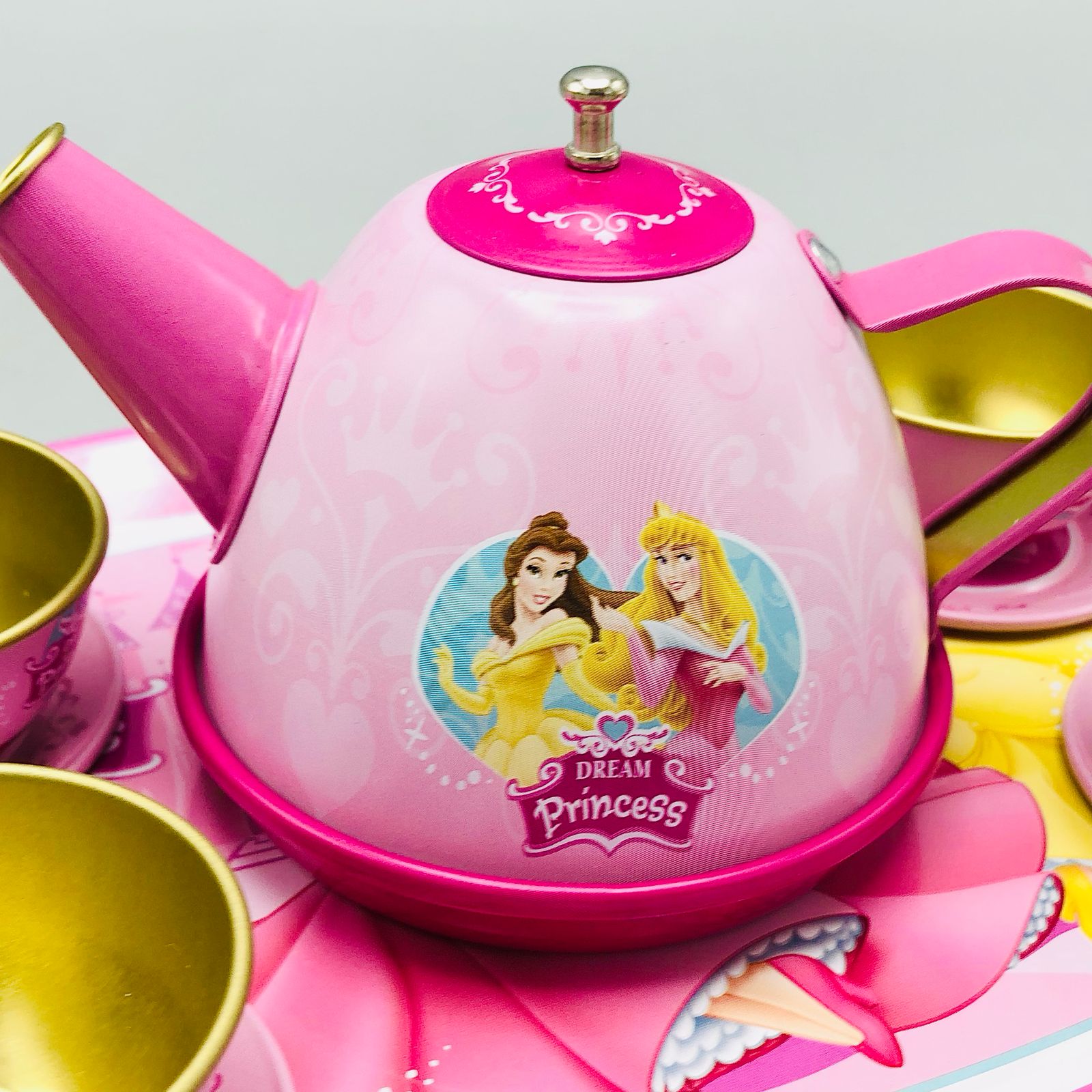 Pink toy tea set with Disney Princess design on a gray background