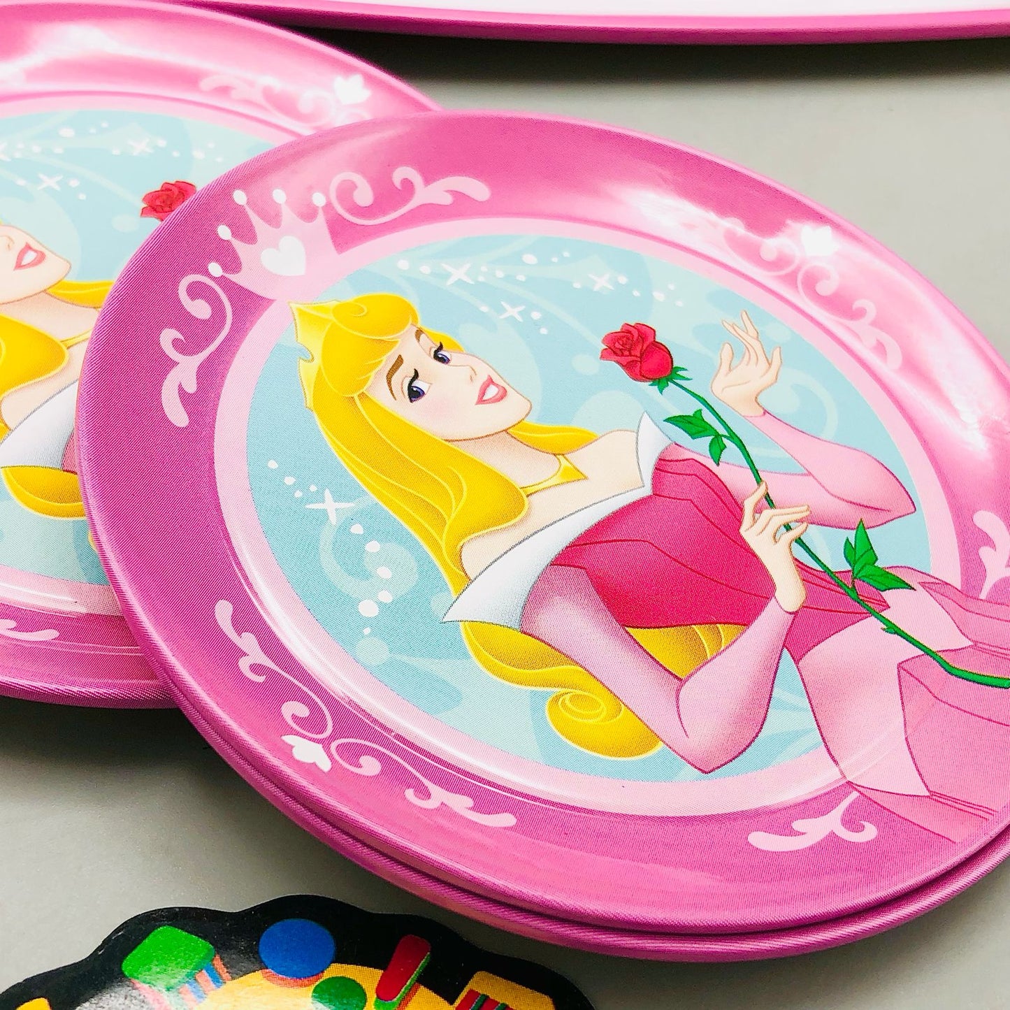 Pink plate with Disney princess design on a light gray surface